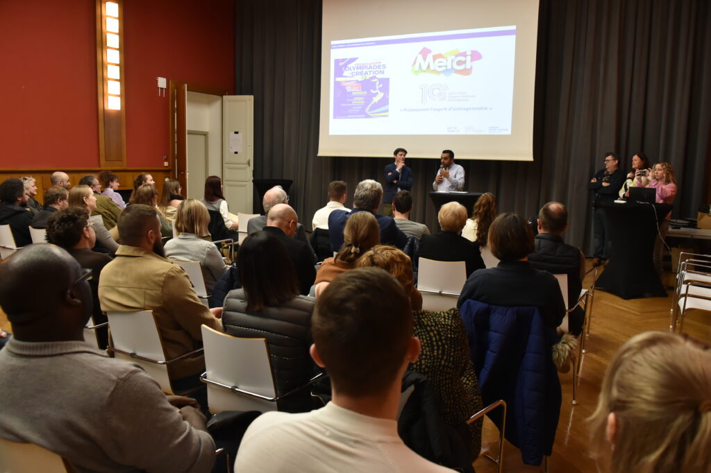 Conférence en salle sur l'entrepreneuriat, public attentif et présentateurs devant un écran avec diapositive Merci.