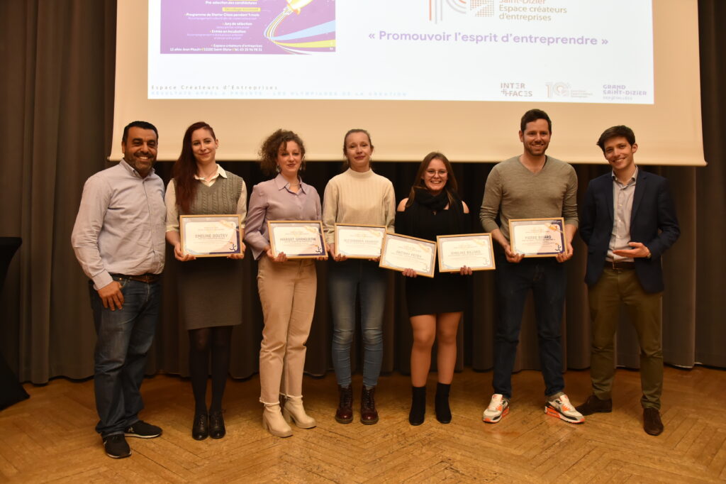Groupe de lauréats souriants tenant des diplômes, célébrant l'esprit d'entreprendre lors d'une cérémonie de remise de prix.