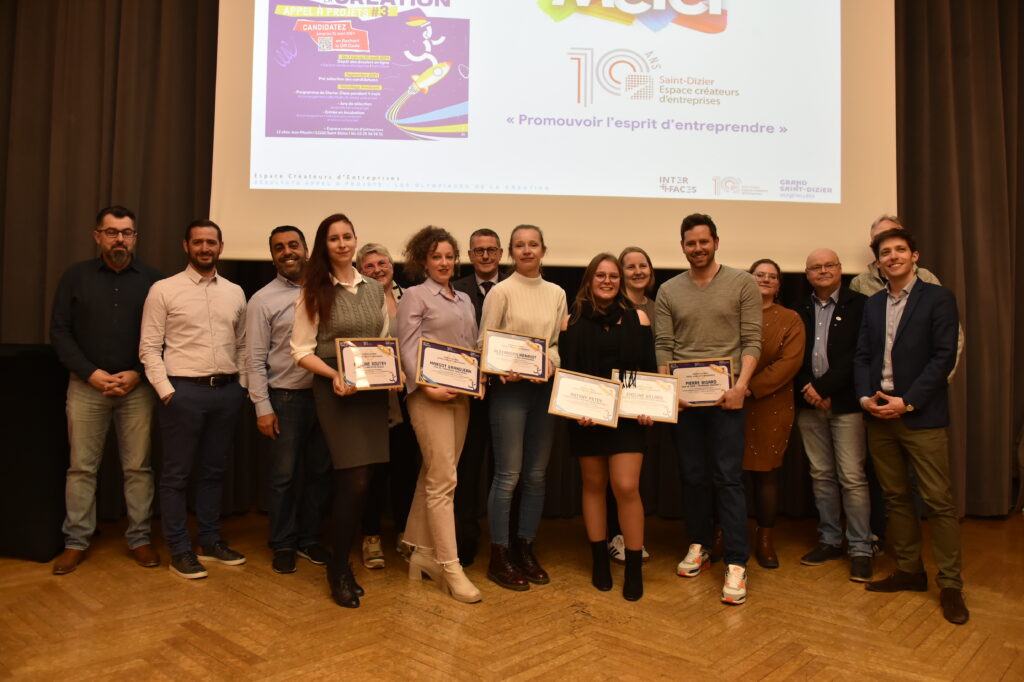 Groupe de personnes posant avec des certificats lors d'un événement de remise de prix pour promouvoir l'entrepreneuriat.