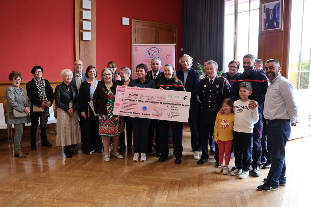 Groupe de personnes remettant un chèque pour soutenir la lutte contre le cancer et les opérations du sein.