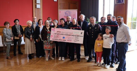 Groupe de personnes remettant un chèque pour soutenir la lutte contre le cancer et les opérations du sein.