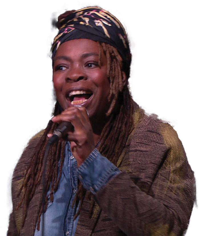Chanteur en concert, tenant un micro, vêtu d'un turban et d'un pull, exprimant passion et énergie sur scène.